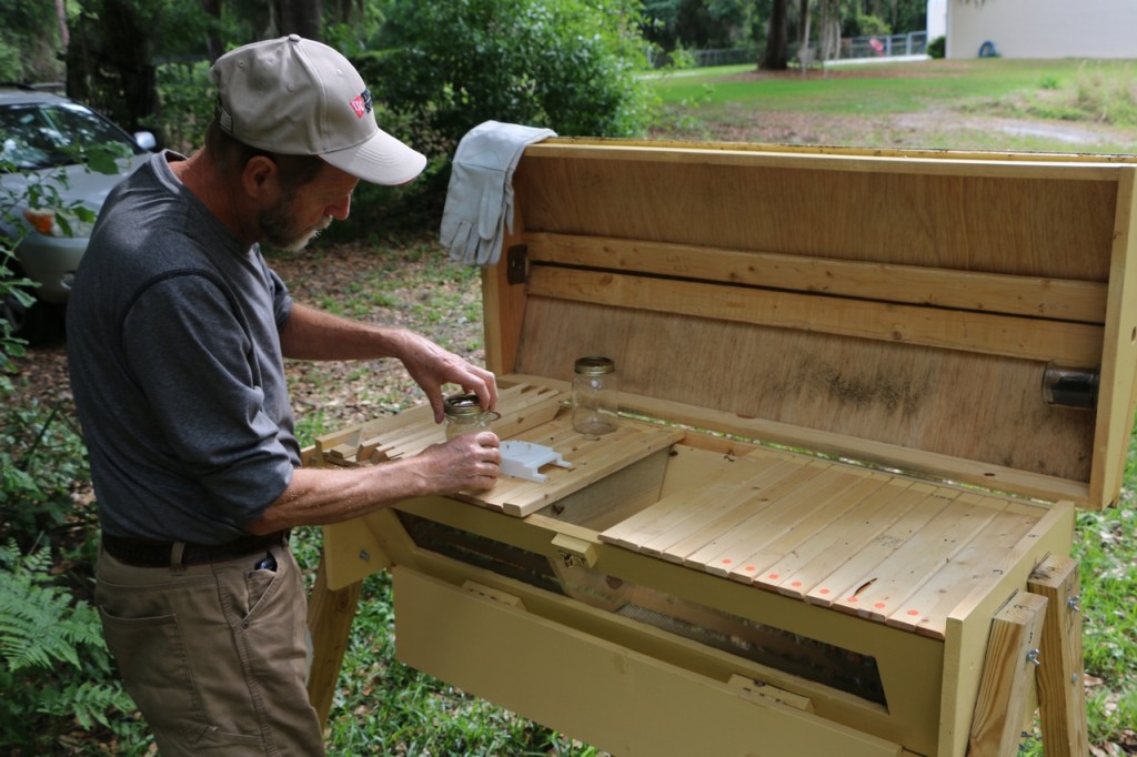 Jim Pescha filling the feeder in his top bar hive. (Stephen Clay McGehee)