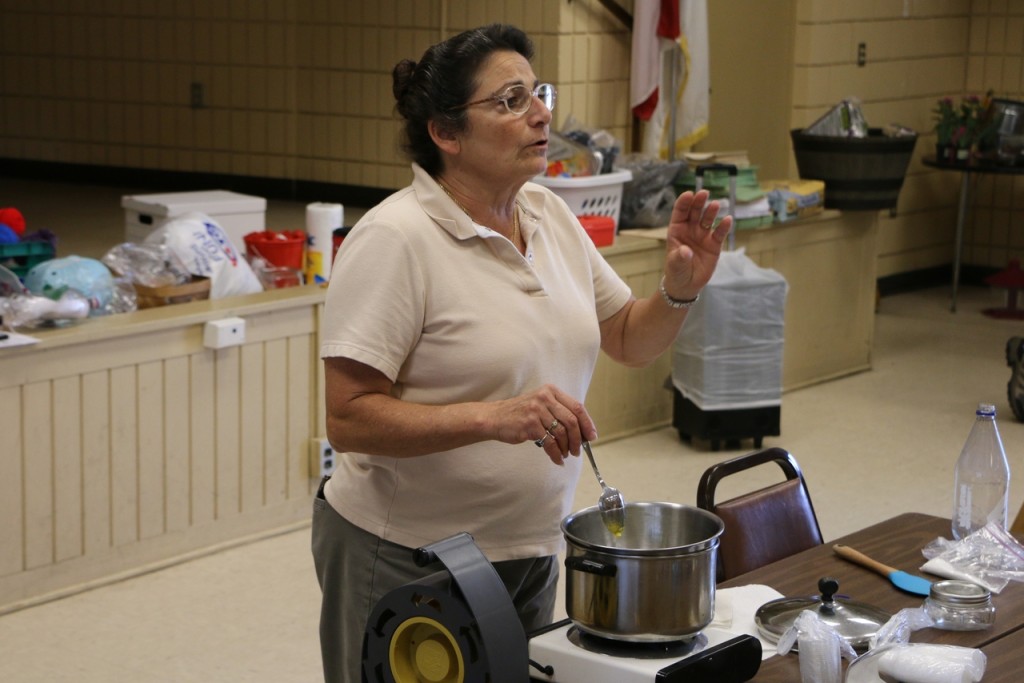 Donna Athearn demonstrating how to make hand lotion using beeswax, olive oil, and other materials.
